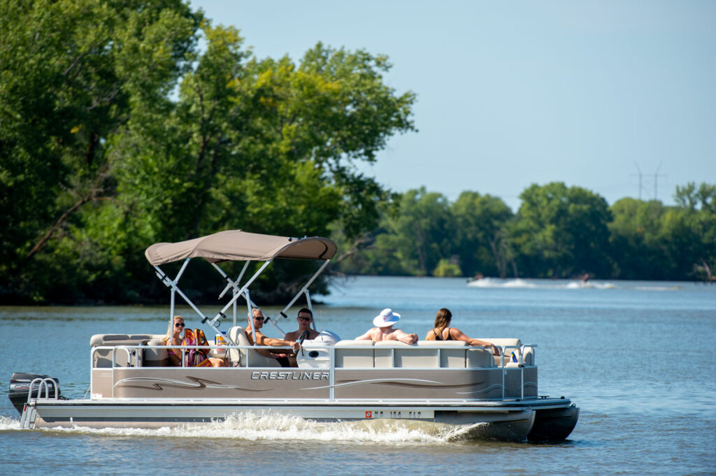 A pontoon boat full of people cruises on Bluestem Lake.