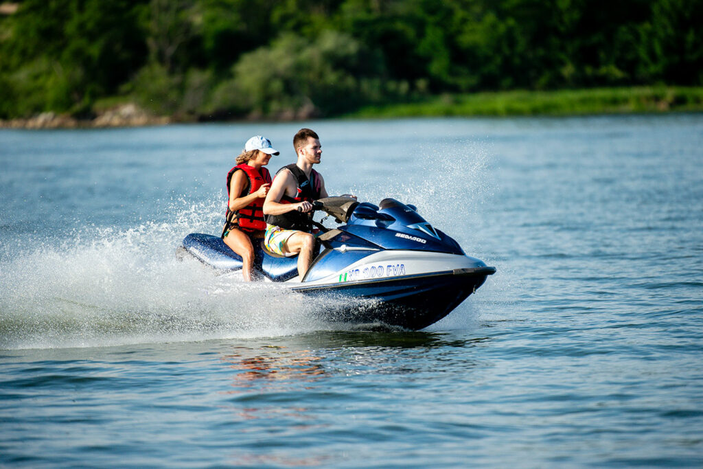 A man and woman ride a personal watercraft across the lake