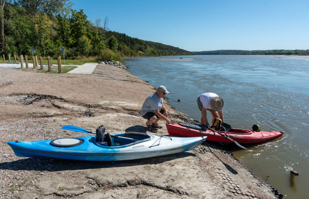 two people prepare to launch their kayaks into the river