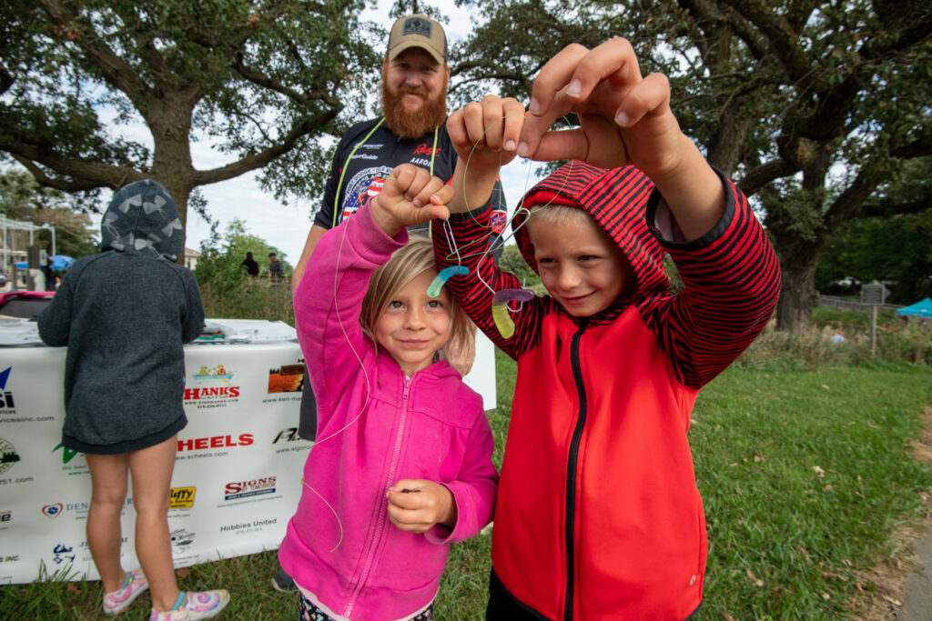 Isaac and Elliana Kulhanek of Minden show off the hooks they tied and baited during the Youth Fishing 101 clinic conducted by Pro Angler Aaron Petersen of Rockwell, Iowa, at the Missouri River Outdoor Expo at Ponca State Park in Dixon County. Eric Fowler, September 18, 2021. Copyright NEBRASKAland Magazine, Nebraska Game and Parks Commission.