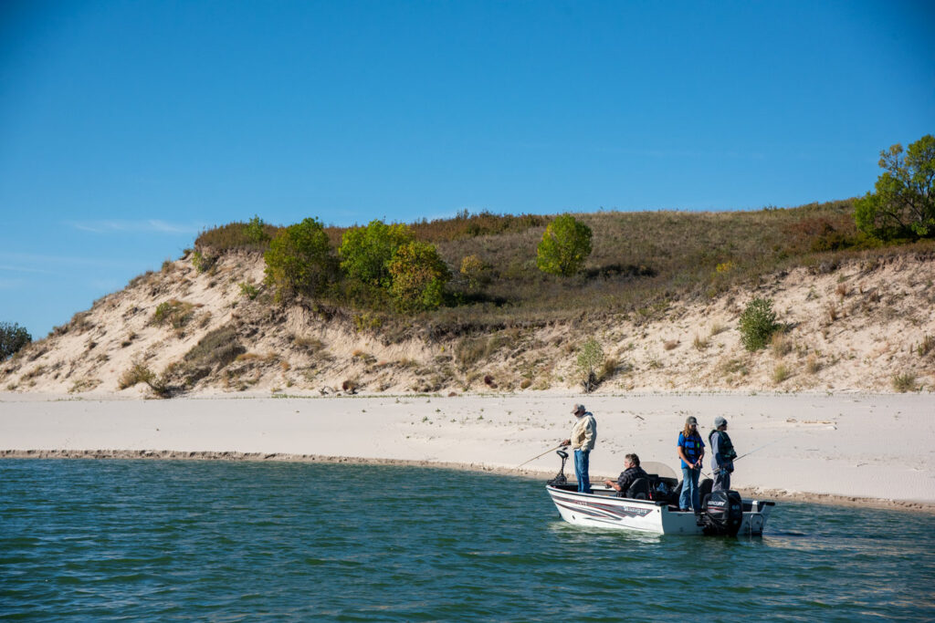 A family fishes from a boat along the coastline of Merritt Reservoir