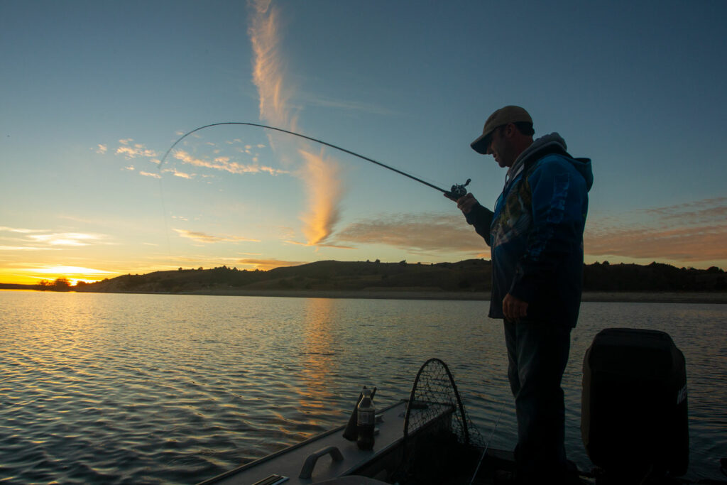A man, silhouetted against a setting sunfishes, at Merritt Reservoir.