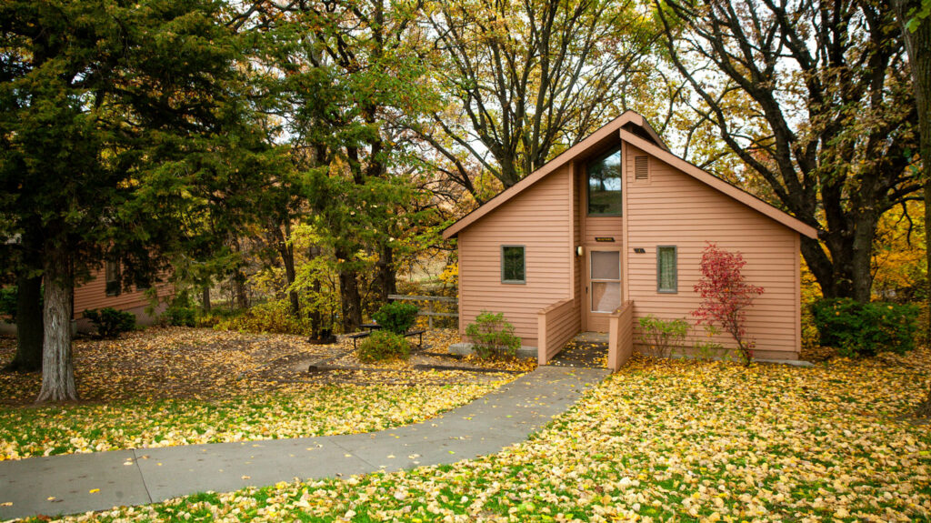 a cabin surrounded by green and yellow fall foliage