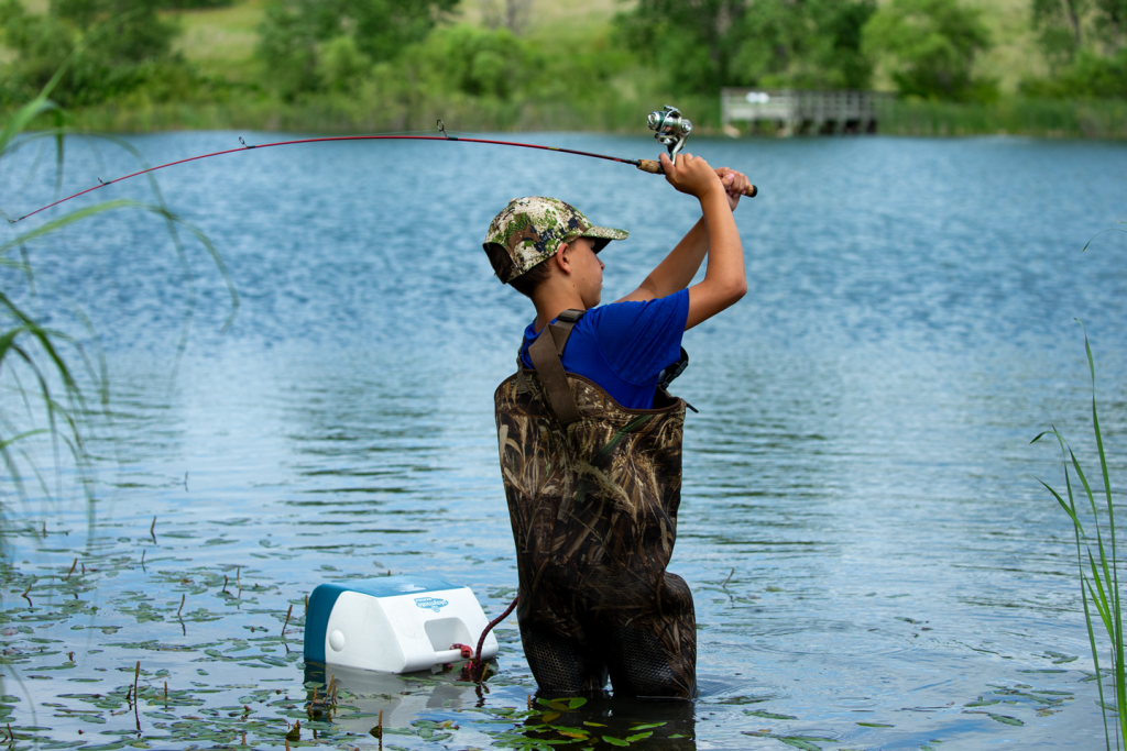 A boy fishes in hip waders