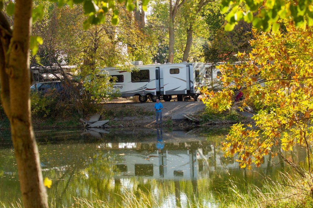 A man fishing the pond, an RV in the background