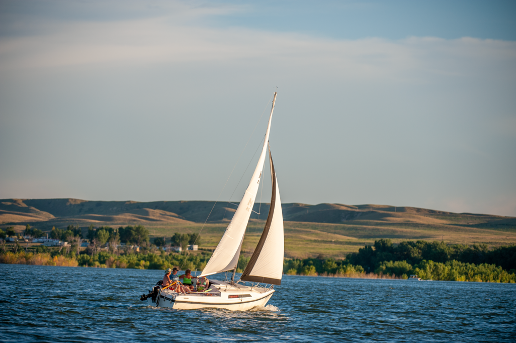 A sailboat on the lake is bright white against a blue sky
