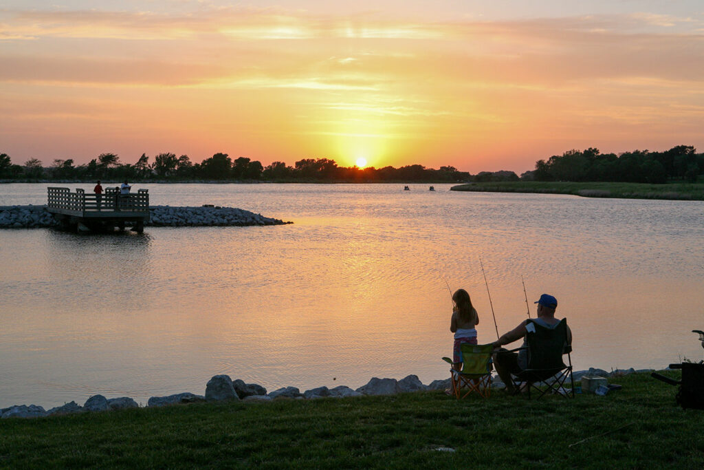 A man and child are silhouetted by the setting sun while they fish at Memphis Lake.