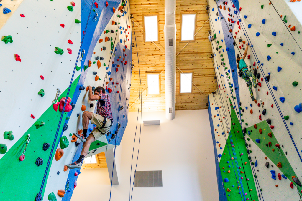 Two people scaling an indoor rock climbing wall.