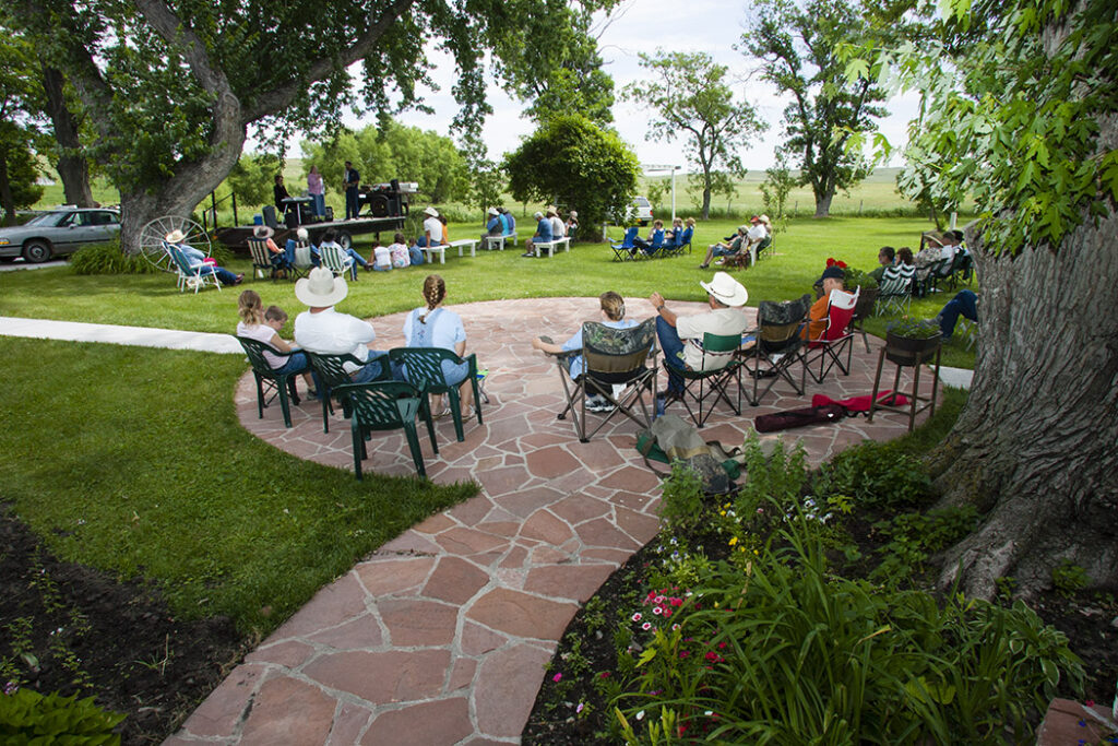 visitors sit in camp chairs at a small outdoor concert