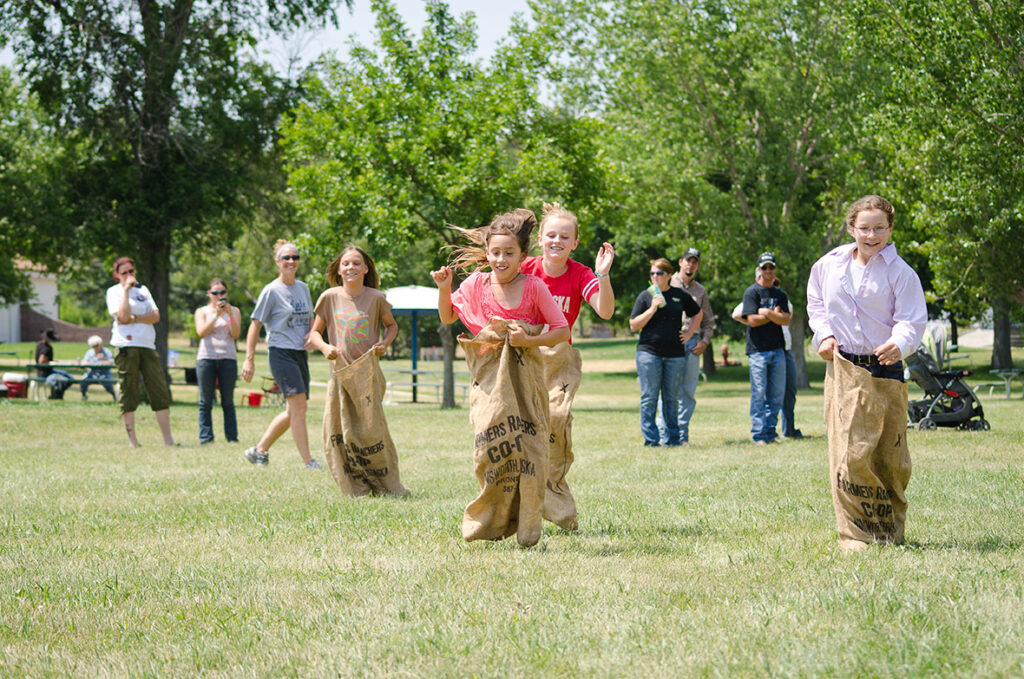 many smiling visitors watch children compete in a sack race