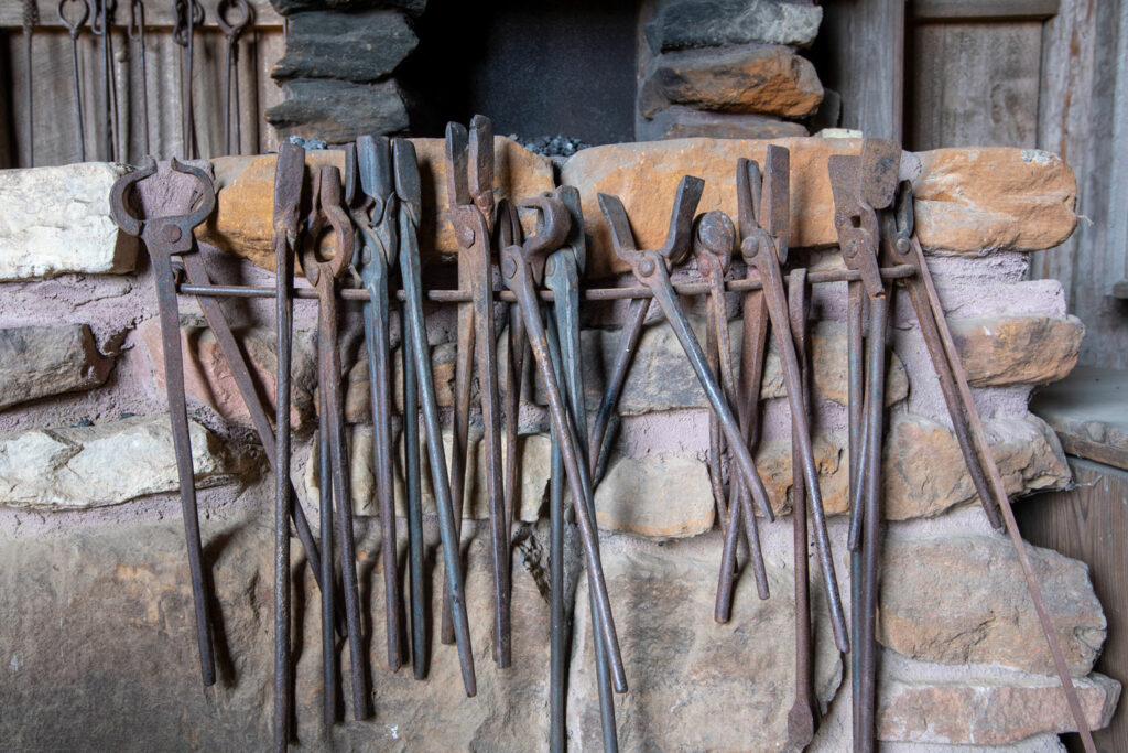 Antique tools used at a blacksmith forge hang on a rod.