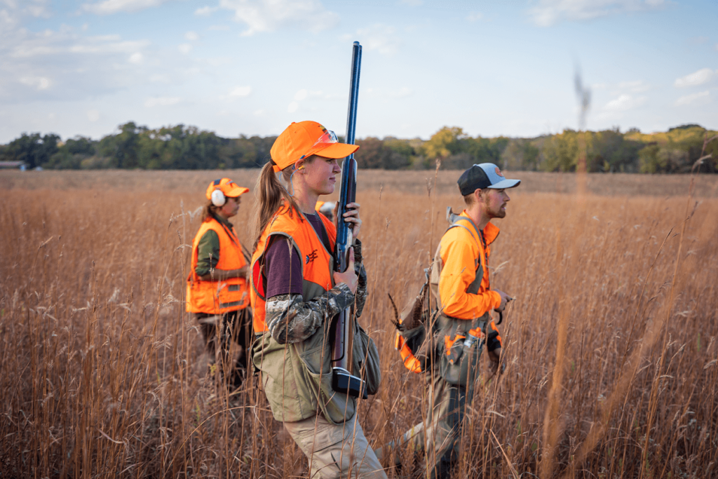 A girl and two others hunt in a prairie