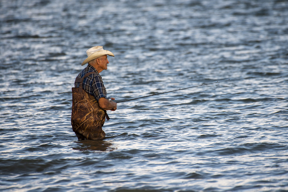 man standing in water fishing