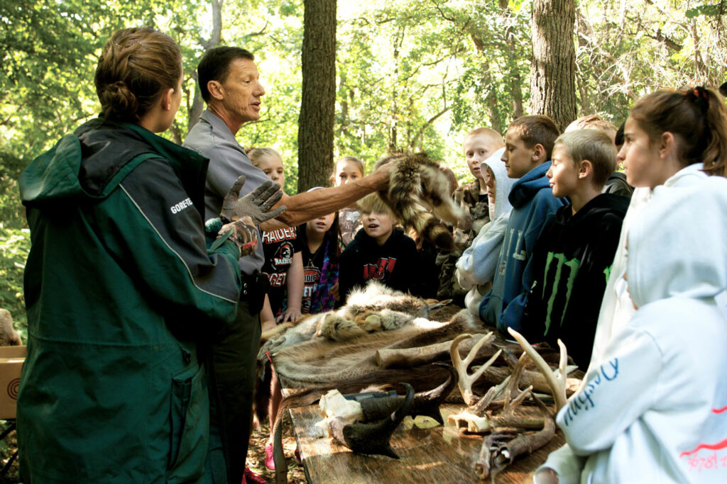 A conservation officer teaches a group of kids about wildlife fur and antler identification