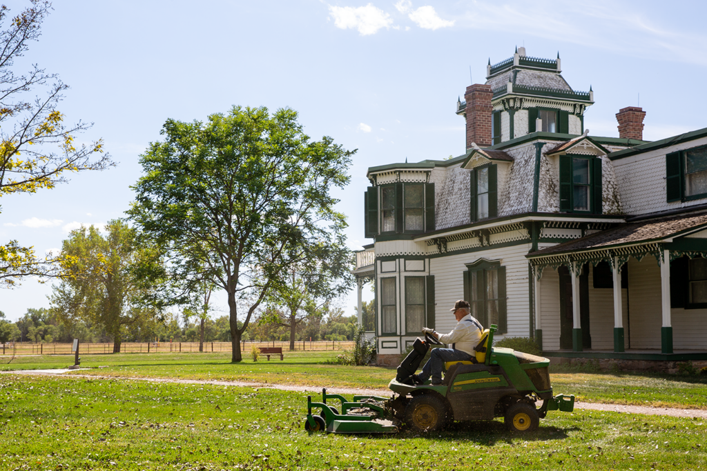 A man mows using a rider lawnmower outside of the historic mansion at Buffalo Bill State Historical Park in Nebraska