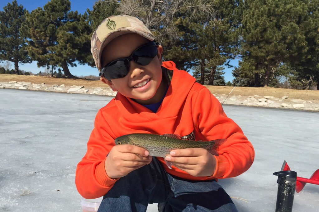 while ice fishing, a young person holds a trout they caught