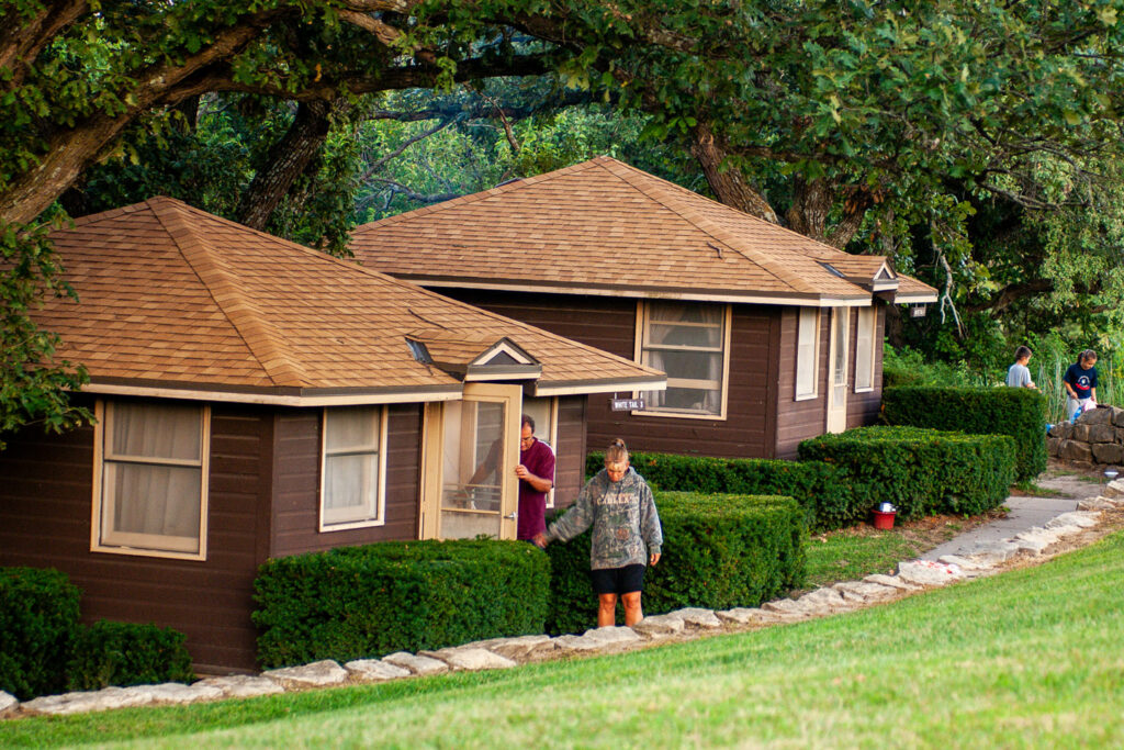 two cabins are nestled in the woods with shrubs around them