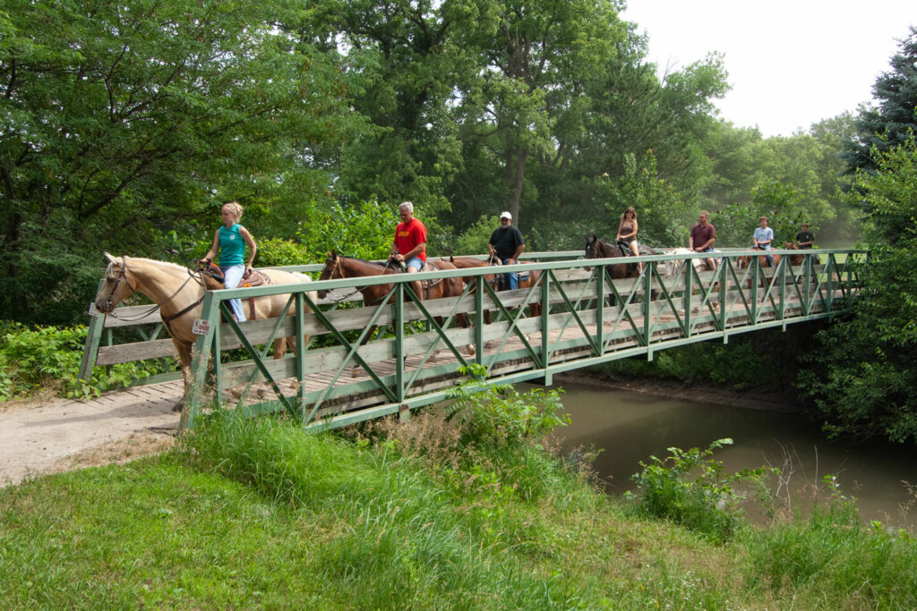 Horseback riders crossing a bridge.