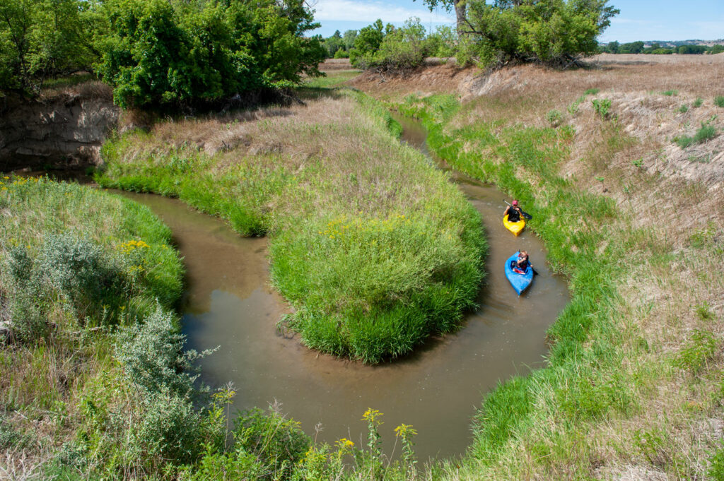 Two people kayak a bend in the river