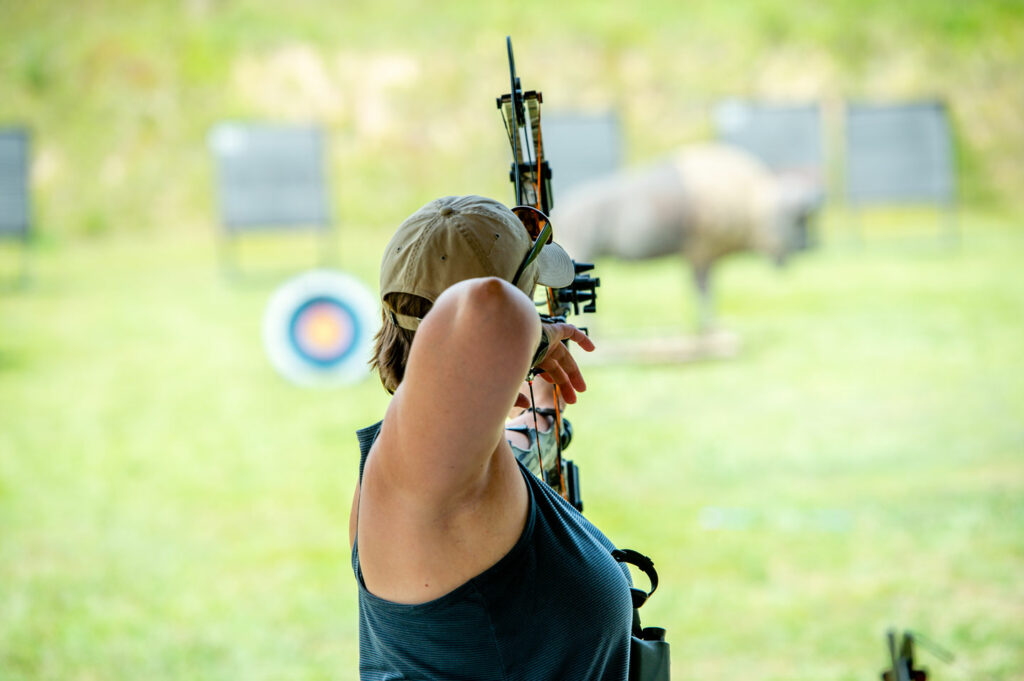 A woman takes aim at an archery target down range.