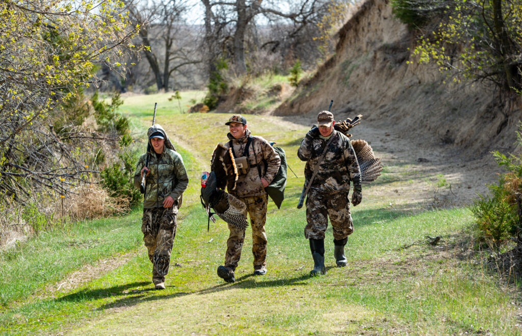 A dad, his son and friend walk along a green path.