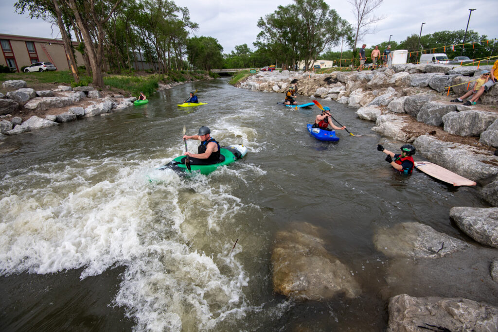 A man paddles down a white water structure on a water trail.