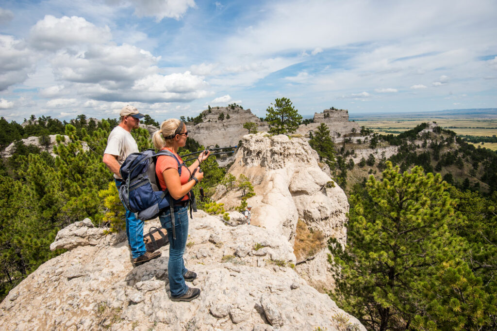 A woman and a man with research equipment on a butte outcrop.