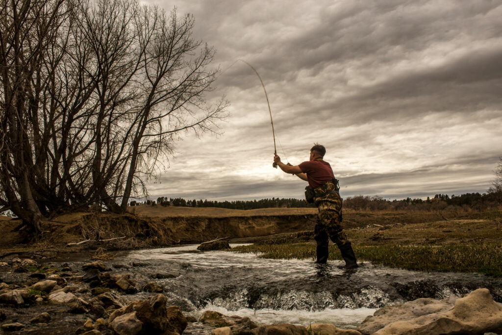 A man fly fishes in a creek