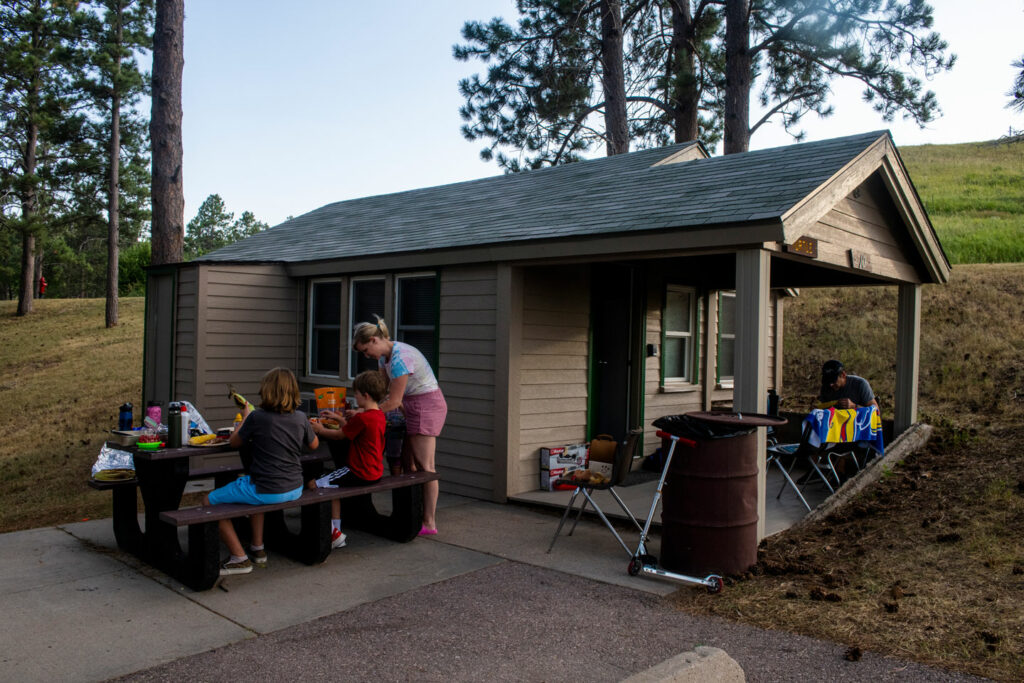visitors sit at the picnic table outside their modern cabin