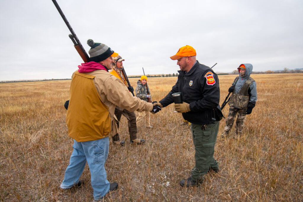 A conservation officer shakes hands with a hunter.