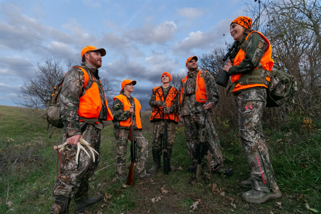 A group of male and female hunters talk.