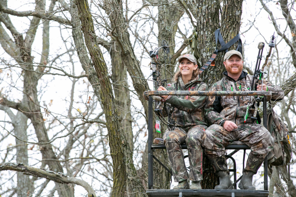 A man and woman hunt from a tree stand.