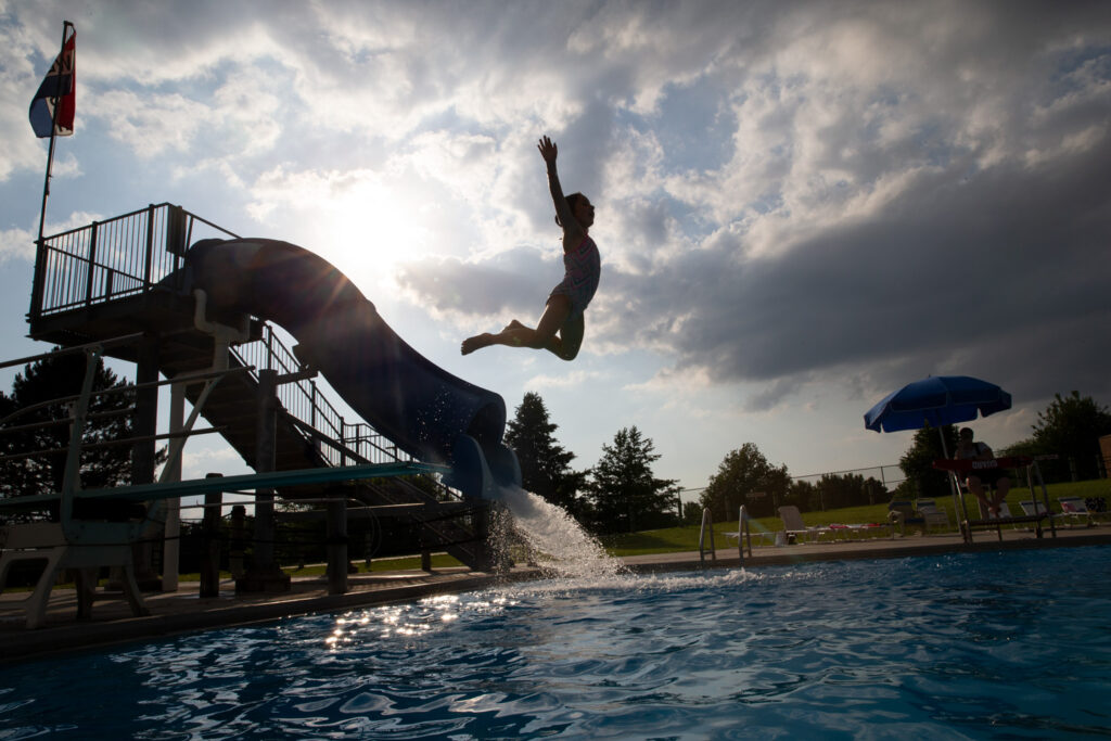 A girl jumps off a diving board into a pool.