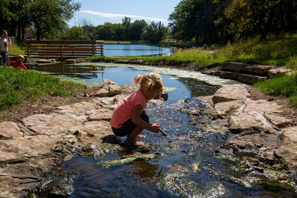 A girl plays in a manicured creek.