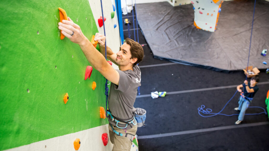 a person climbs a brightly colored indoor climbing wall