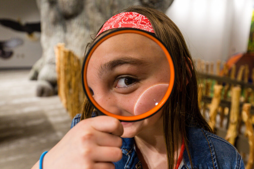 girl looking at camera through magnifying glass