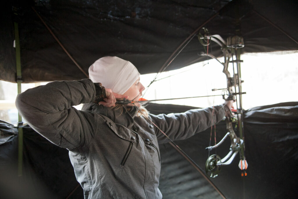 A woman takes aim with her bow and arrow