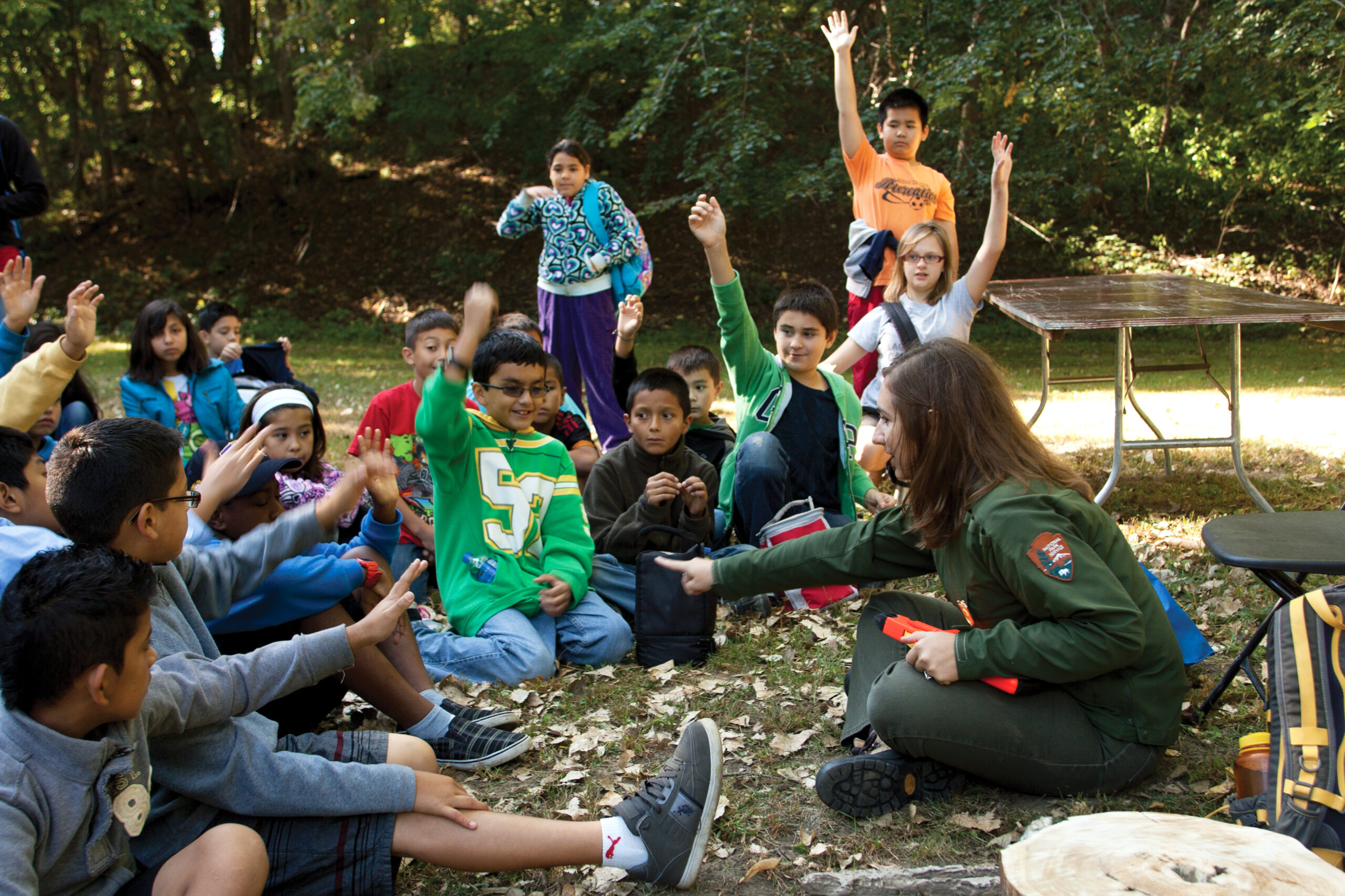 A wildlife expert asks children a question with kids hands in the air.