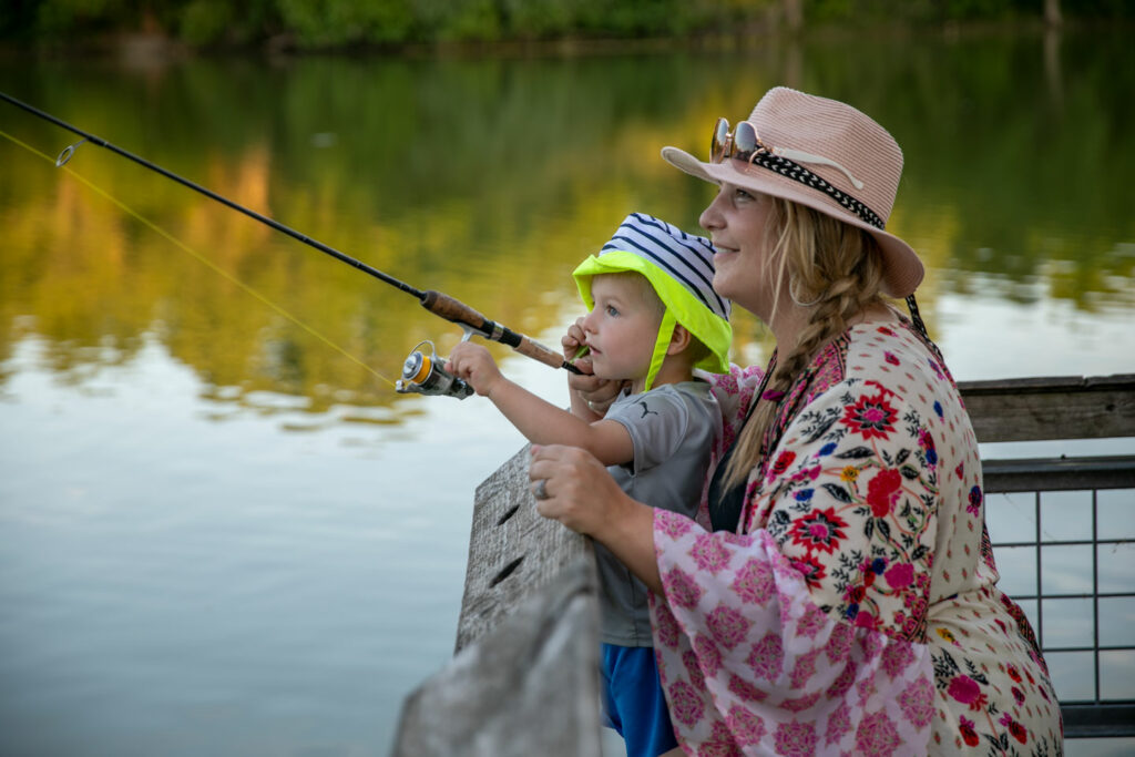 A woman helps her toddler fish