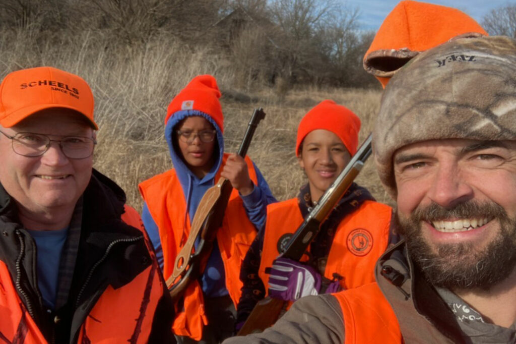 Two men and two boys pose for a selfie while upland hunting.