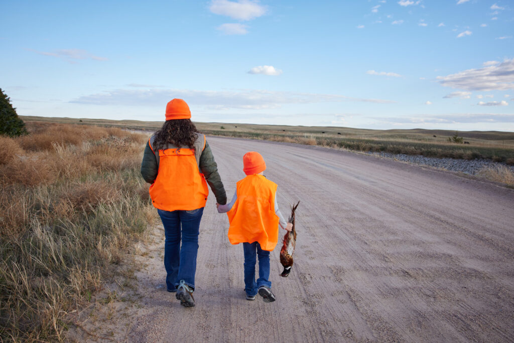 A woman and boy walk down the road with their pheasant take