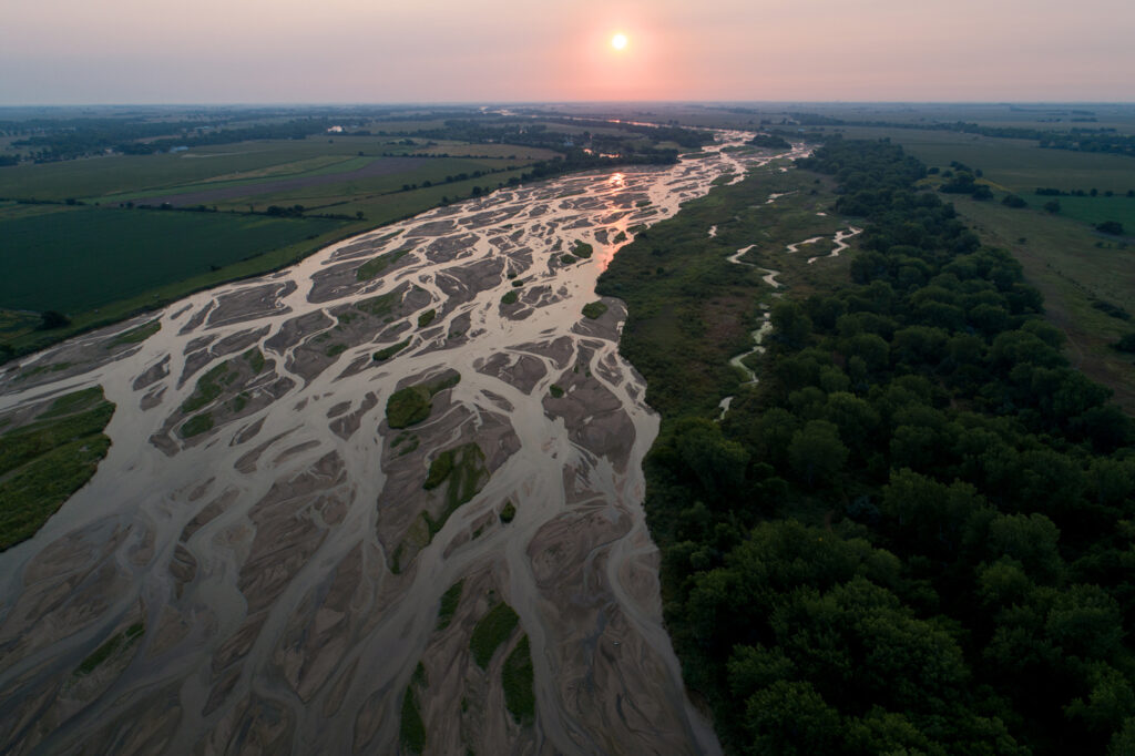 A scenic aerial view of the Platte River with the sun on the horizon.