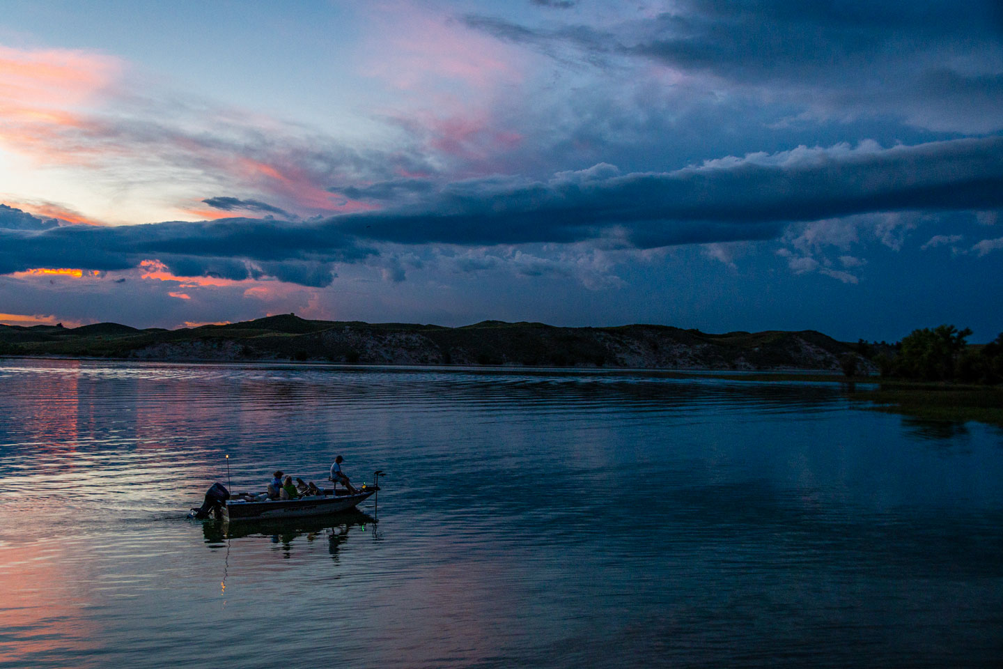 Anglers fish from a boat at dusk in the Nebraska sandhills.