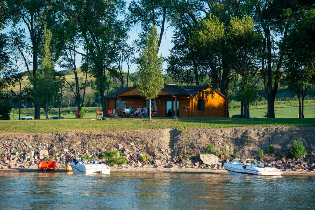 Families relax in front of the cabins in the Weigand-Burbach area at Lewis and Clark Lake SRA, a reservoir on the Missouri River in Knox County.  Fowler, July 24, 2015. Copyright NEBRASKAland Magazine, Nebraska Game and Parks Commission.