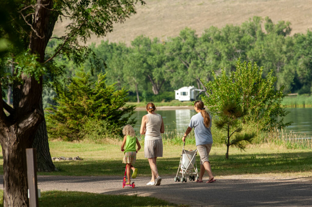 Two women and two small children walk along a campground path next to the lake at Lake Ogallala SRA.