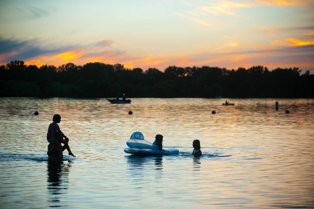 A family swims in a lake at sunset during summer