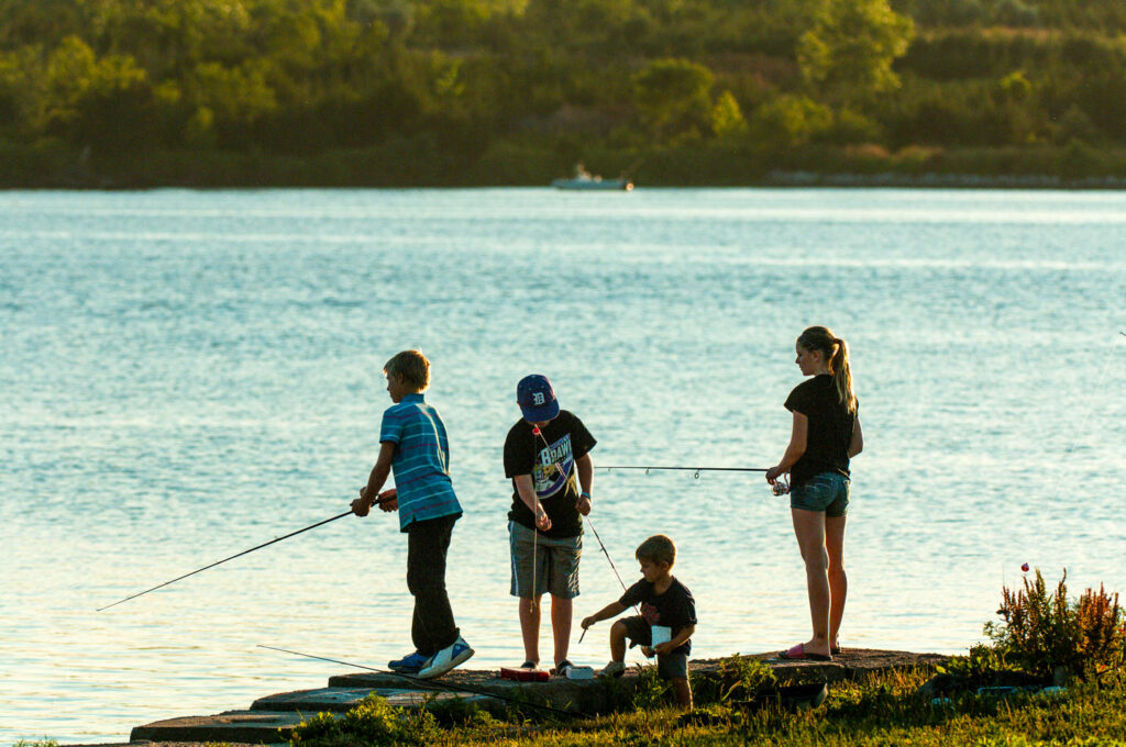 Four children fishing at a lake on a clear summer day