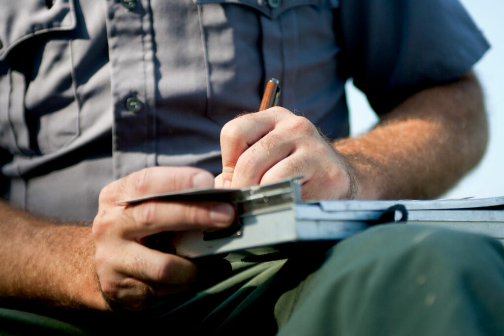 Close-up of a Conservation Officer writing a ticket for a fishing violation.