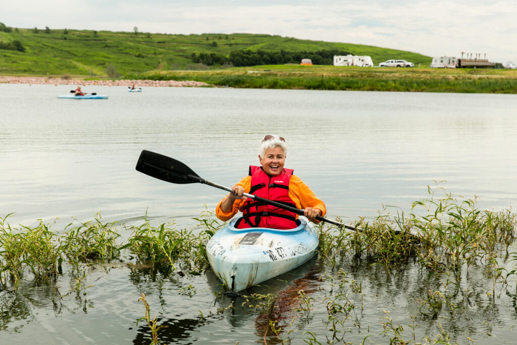 A woman grins from a kayak