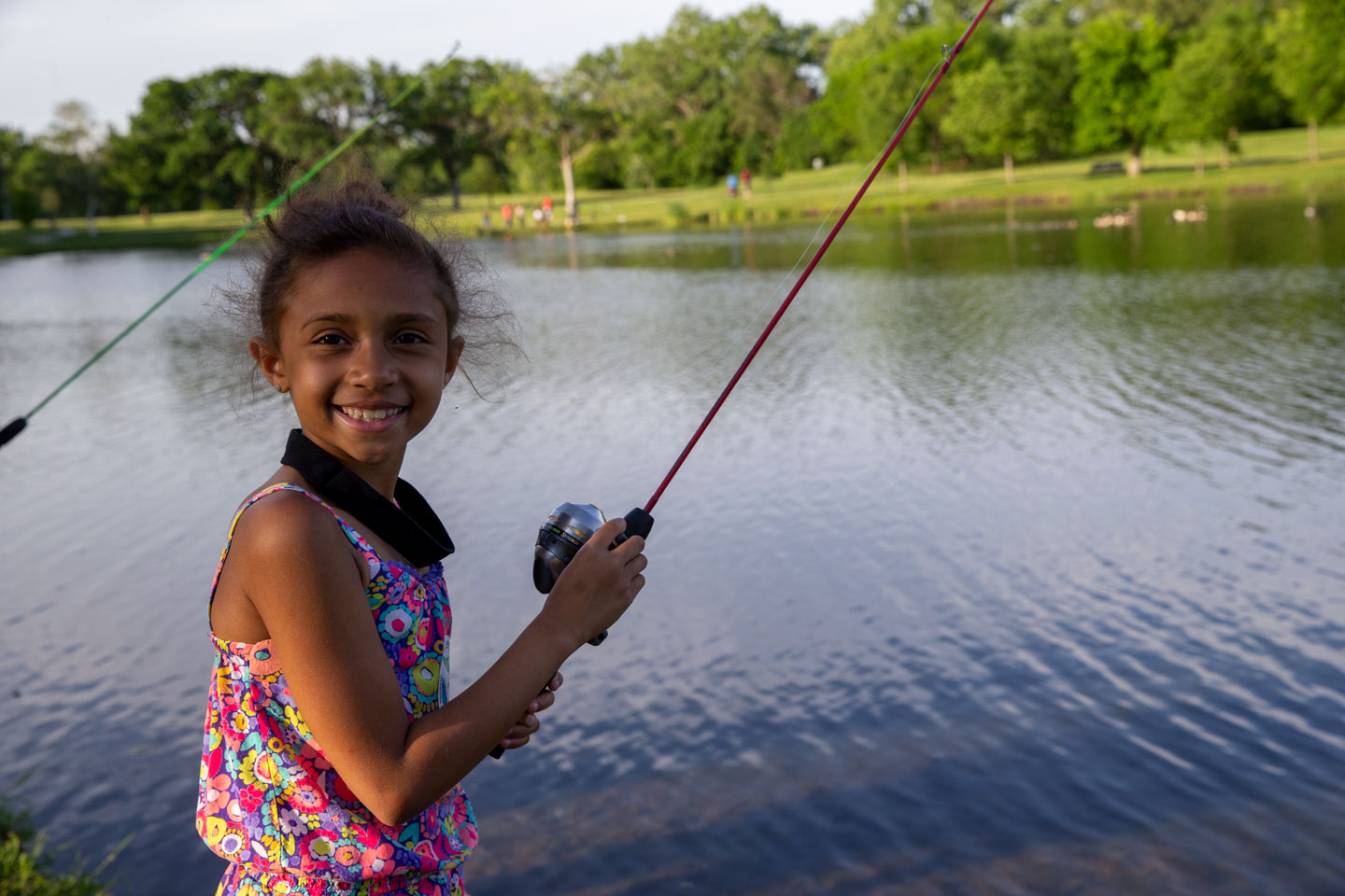 A small girl grins with her fishing pole